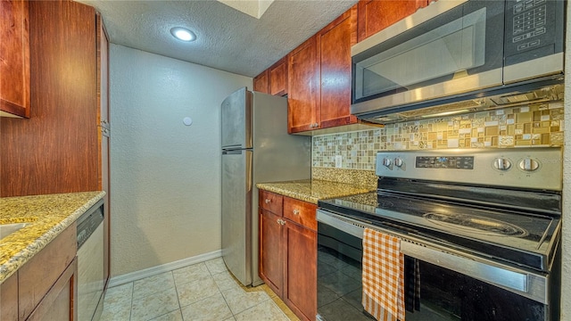 5112 Conroy Rd Unit 24, Orlando, FL 32811 - kitchen featuring stainless steel appliances, tasteful backsplash, a textured ceiling, light stone counters, and light tile patterned floors