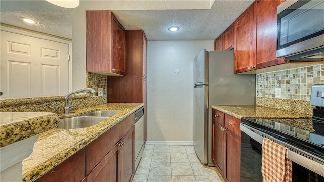5112 Conroy Rd Unit 24, Orlando, FL 32811 - kitchen with appliances with stainless steel finishes, a textured ceiling, decorative backsplash, reddish brown cabinets, and light stone countertops