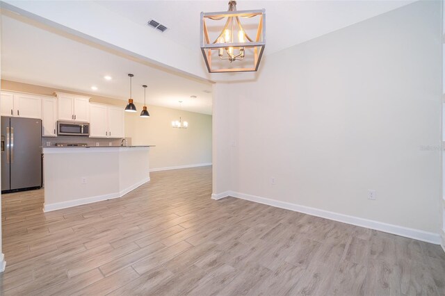 1173 Trappers Trail Loop, Champions Gate, FL 33896 - kitchen featuring a chandelier, stainless steel appliances, light wood finished floors, white cabinets, and open floor plan