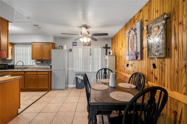 1 Coyer Rd, Haines City, FL 33844 - kitchen featuring brown cabinetry, black microwave, wood walls, a ceiling fan, and light tile patterned floors