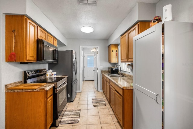 1 Coyer Rd, Haines City, FL 33844 - kitchen featuring black microwave, stainless steel range with electric stovetop, freestanding refrigerator, a textured ceiling, and brown cabinets