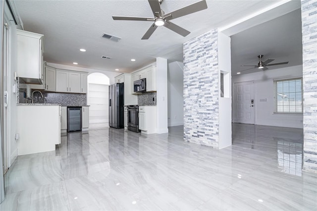 1101 Sandestin Way, Orlando, FL 32824 - kitchen with stainless steel appliances, ceiling fan, open floor plan, beverage cooler, and arched walkways