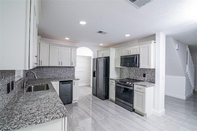 1101 Sandestin Way, Orlando, FL 32824 - kitchen featuring appliances with stainless steel finishes, wine cooler, arched walkways, light stone counters, and backsplash