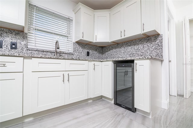 1101 Sandestin Way, Orlando, FL 32824 - kitchen with beverage cooler, white cabinets, light stone counters, and decorative backsplash
