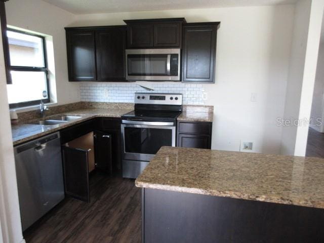 1740 Chatham Green Cir, Ruskin, FL 33570 - kitchen featuring appliances with stainless steel finishes, dark wood-style floors, decorative backsplash, and light stone counters