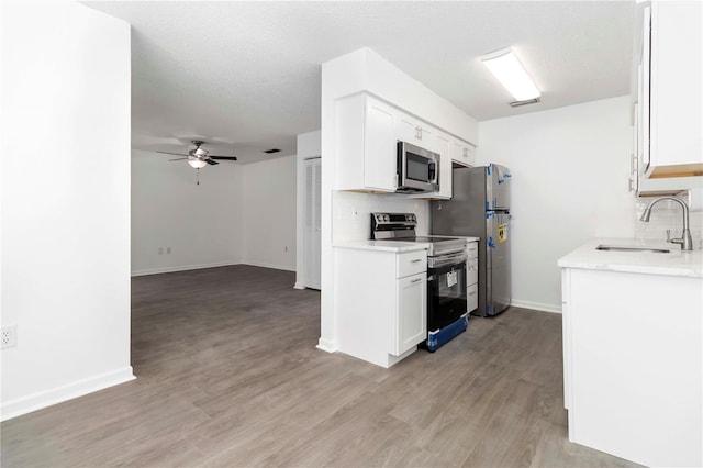 840 Center Ave Unit 80, Daytona Beach, FL 32117 - kitchen featuring appliances with stainless steel finishes, tasteful backsplash, light countertops, light wood-type flooring, and white cabinets