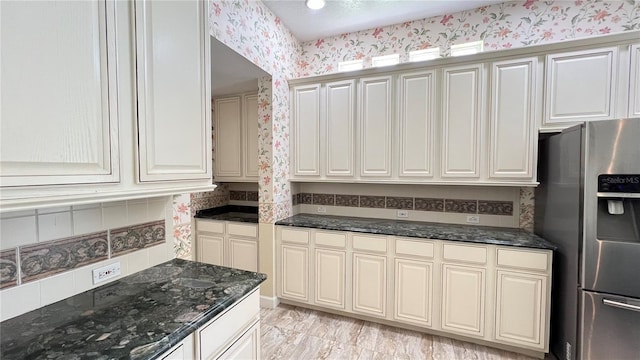 934 Westpark Dr, Celebration, FL 34747 - kitchen with stainless steel fridge with ice dispenser, wallpapered walls, dark stone countertops, and light marble finish floors