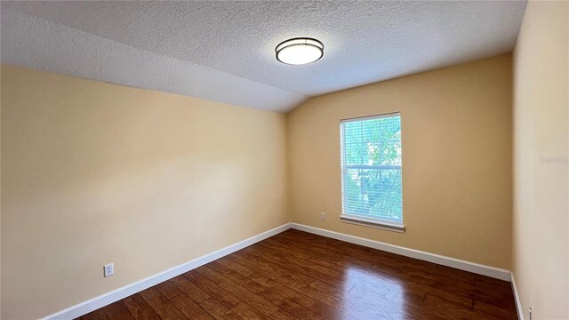 934 Westpark Dr, Celebration, FL 34747 - empty room with dark wood-type flooring, vaulted ceiling, and a textured ceiling