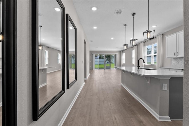 1717 Hilltop Dr, Dundee, FL 33838 - kitchen featuring light wood-type flooring, white cabinetry, a large island with sink, open floor plan, and a kitchen breakfast bar