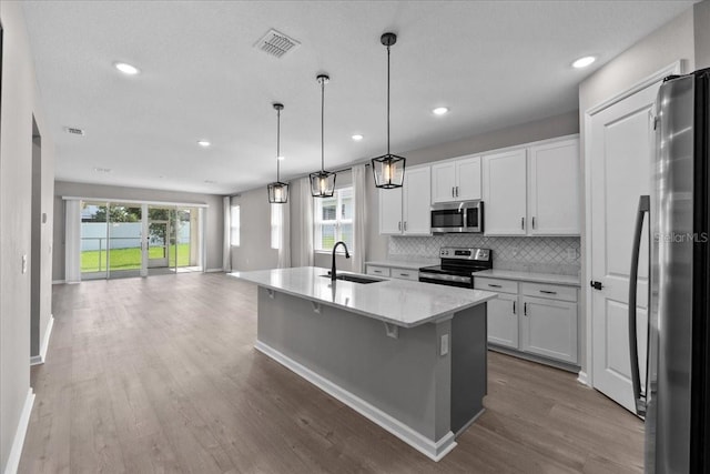 1717 Hilltop Dr, Dundee, FL 33838 - kitchen with appliances with stainless steel finishes, open floor plan, wood finished floors, backsplash, and white cabinetry