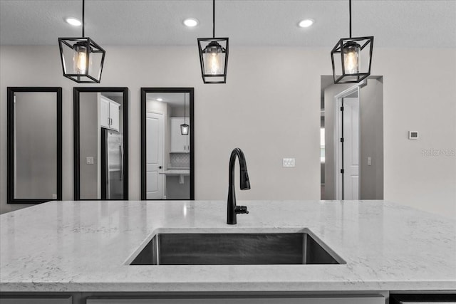 1717 Hilltop Dr, Dundee, FL 33838 - kitchen with stainless steel refrigerator, light stone counters, hanging light fixtures, a textured ceiling, and recessed lighting