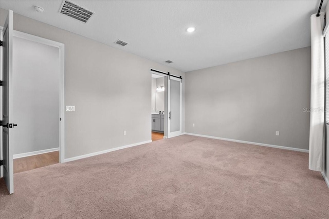 1717 Hilltop Dr, Dundee, FL 33838 - unfurnished bedroom featuring a barn door, carpet, recessed lighting, and ensuite bath