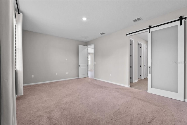 1717 Hilltop Dr, Dundee, FL 33838 - unfurnished bedroom featuring a barn door, light carpet, and recessed lighting