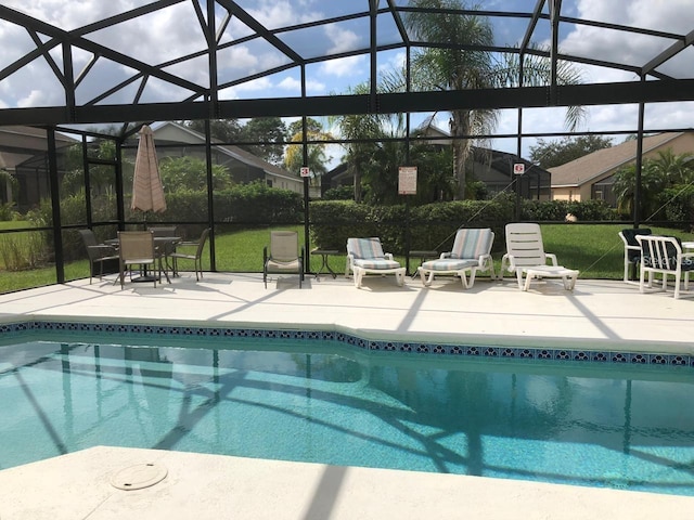 outdoor pool featuring a patio, glass enclosure, and a lawn
