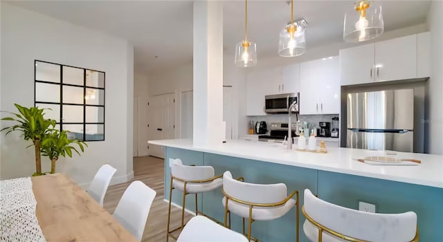 8103 Coconut Palm Way Unit 203, Kissimmee, FL 34747 - kitchen with stainless steel appliances, white cabinetry, a breakfast bar area, and decorative light fixtures