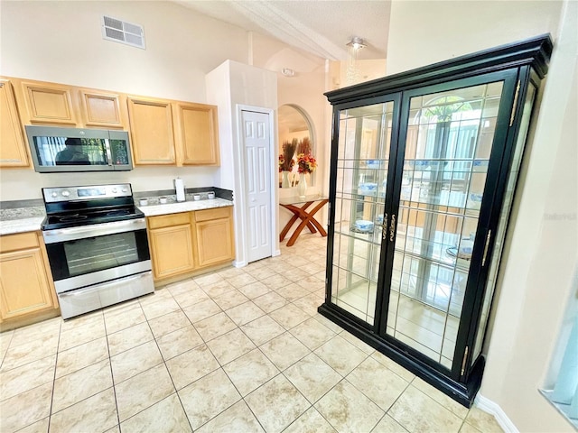 162 Seneca Point Trl, Kissimmee, FL 34746 - kitchen featuring stainless steel appliances, light brown cabinetry, arched walkways, and light countertops