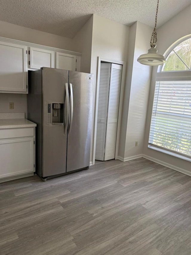 2833 Falling Tree Cir, Orlando, FL 32837 - kitchen featuring stainless steel fridge with ice dispenser, white cabinets, light wood-type flooring, and a textured ceiling