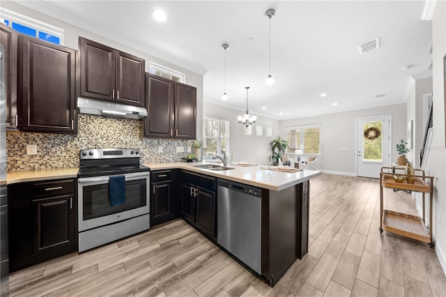9121 Laureate Blvd, Orlando, FL 32827 - kitchen with stainless steel appliances, under cabinet range hood, light countertops, crown molding, and backsplash