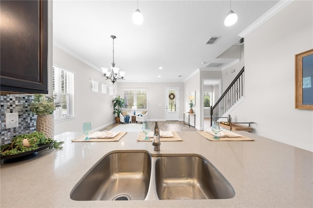 9121 Laureate Blvd, Orlando, FL 32827 - kitchen featuring dark brown cabinetry, light countertops, hanging light fixtures, crown molding, and a chandelier