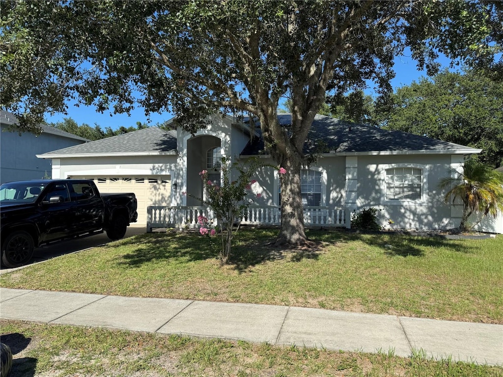 478 Acacia Tree Way, Kissimmee, FL 34758 - view of front facade with an attached garage, a front yard, roof with shingles, and stucco siding