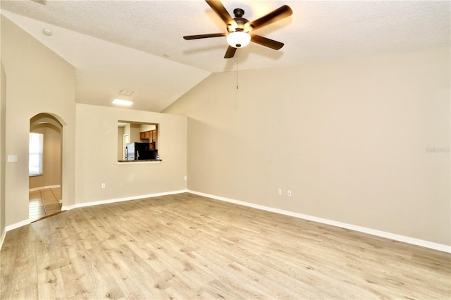 1749 Christina Lee Ln, Saint Cloud, FL 34769 - unfurnished room featuring ceiling fan, light wood finished floors, arched walkways, lofted ceiling, and a textured ceiling
