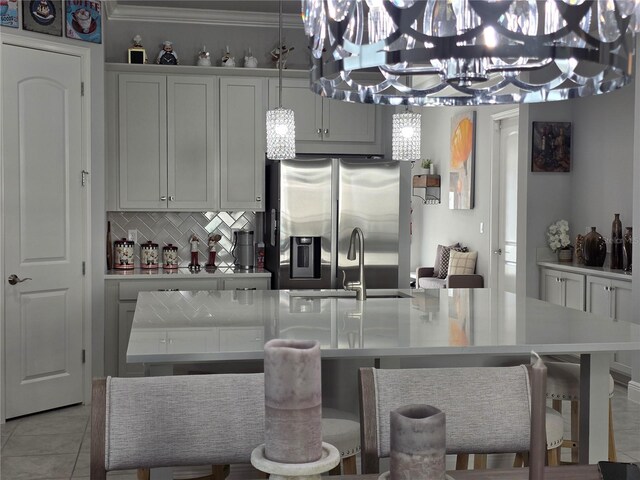 2853 Willowseed Ln, Saint Cloud, FL 34772 - kitchen with stainless steel fridge with ice dispenser, tasteful backsplash, a chandelier, light countertops, and a kitchen island with sink