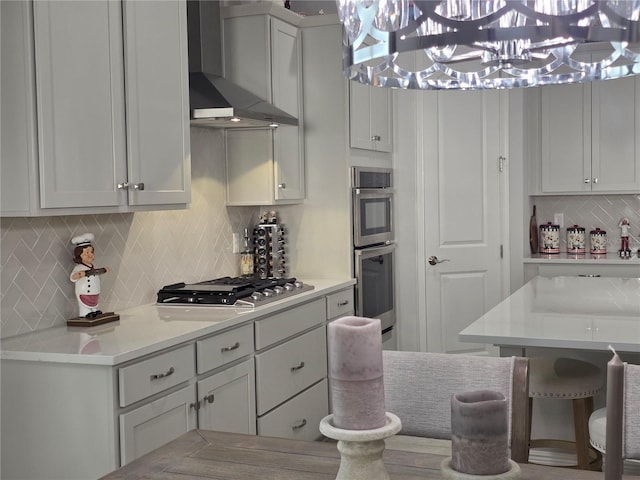 2853 Willowseed Ln, Saint Cloud, FL 34772 - kitchen with wall chimney range hood, appliances with stainless steel finishes, a chandelier, backsplash, and light countertops