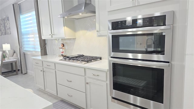 2853 Willowseed Ln, Saint Cloud, FL 34772 - kitchen with appliances with stainless steel finishes, wall chimney range hood, light countertops, decorative backsplash, and white cabinets