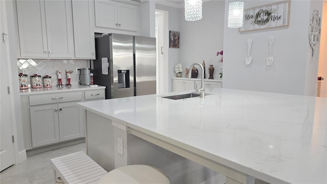 2853 Willowseed Ln, Saint Cloud, FL 34772 - kitchen featuring stainless steel fridge, backsplash, decorative light fixtures, light stone countertops, and light tile patterned flooring