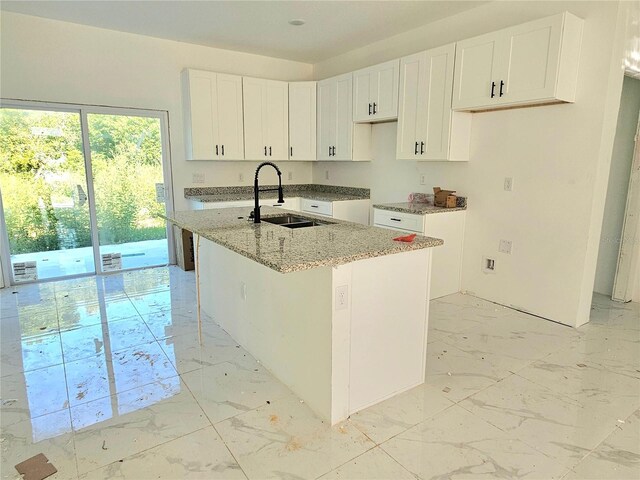 1236 N Virginia Ave, Lakeland, FL 33805 - kitchen featuring light marble finish flooring, light stone countertops, white cabinets, and a center island with sink