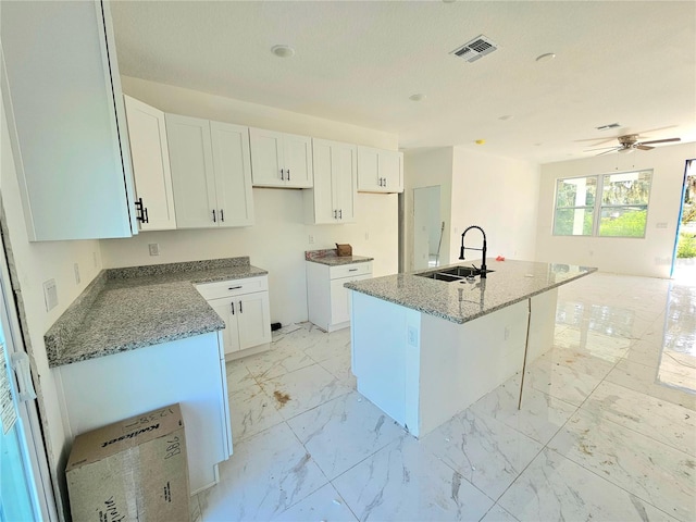 1236 N Virginia Ave, Lakeland, FL 33805 - kitchen with light marble finish flooring, stone counters, a center island with sink, and white cabinetry