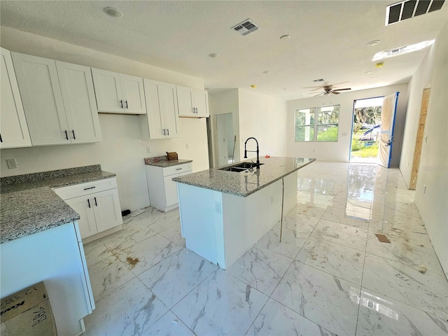 1236 N Virginia Ave, Lakeland, FL 33805 - kitchen featuring white cabinets, a center island with sink, and dark stone countertops