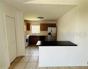 851 Adour Dr Unit A-B, Kissimmee, FL 34759 - kitchen with stainless steel refrigerator with ice dispenser, a peninsula, stove, light tile patterned floors, and dark countertops