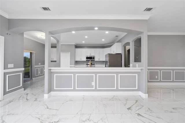 1950 Windward Oaks Ct, Kissimmee, FL 34746 - kitchen with stainless steel appliances, arched walkways, ornamental molding, white cabinets, and a decorative wall