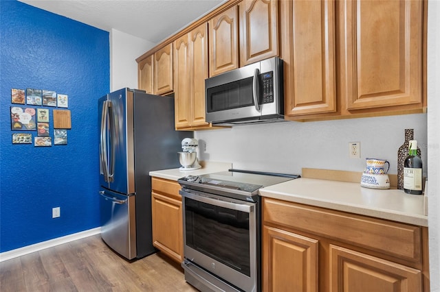 1351 Venezia Ct Unit 201, Davenport, FL 33896 - kitchen featuring stainless steel appliances, light wood-style floors, light countertops, and a textured wall