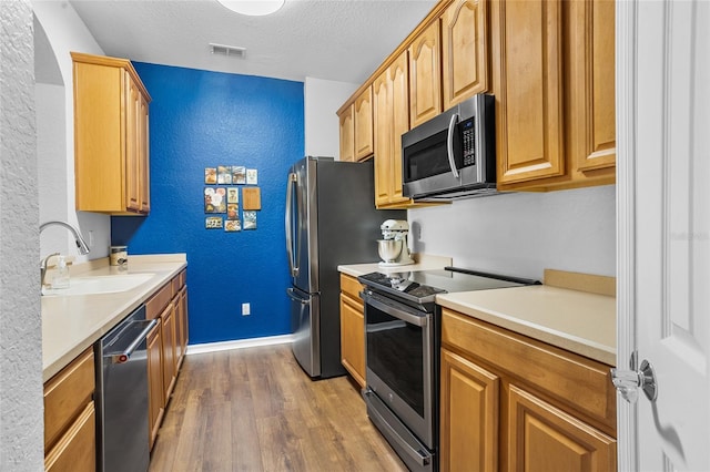 1351 Venezia Ct Unit 201, Davenport, FL 33896 - kitchen with appliances with stainless steel finishes, wood finished floors, a textured wall, light countertops, and a textured ceiling