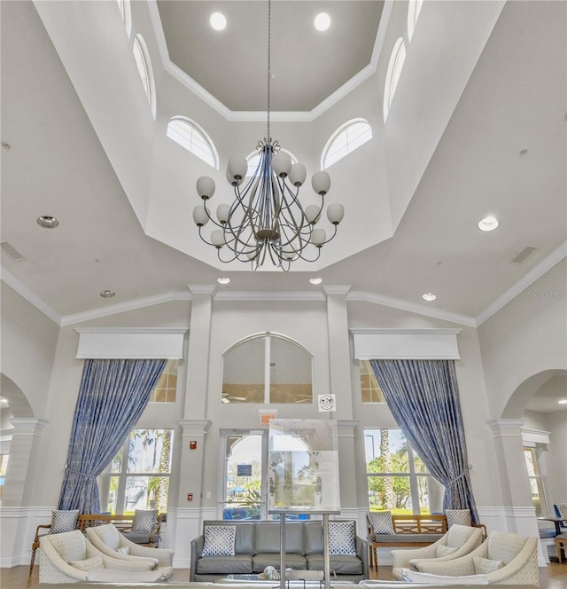 1351 Venezia Ct Unit 201, Davenport, FL 33896 - living area featuring a towering ceiling, arched walkways, ornate columns, a decorative wall, and plenty of natural light