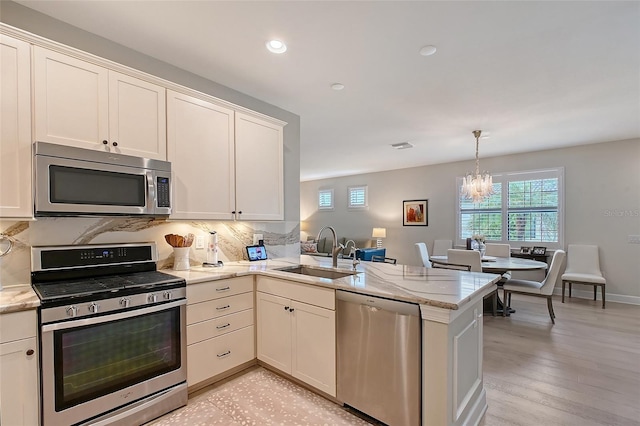 17109 Kenton Ter, Bradenton, FL 34202 - kitchen with stainless steel appliances, a chandelier, a peninsula, backsplash, and recessed lighting