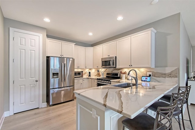 17109 Kenton Ter, Bradenton, FL 34202 - kitchen featuring appliances with stainless steel finishes, light stone counters, a peninsula, light wood-type flooring, and white cabinets