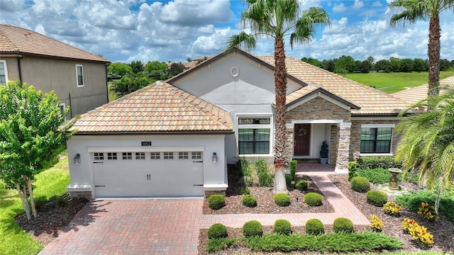 1452 Mickelson Ct, Davenport, FL 33896 - mediterranean / spanish house featuring a tile roof, stone siding, a garage, and decorative driveway