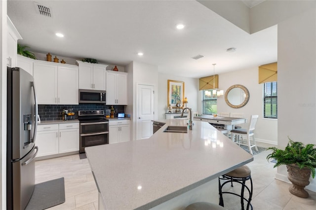 1452 Mickelson Ct, Davenport, FL 33896 - kitchen featuring appliances with stainless steel finishes, tasteful backsplash, white cabinetry, recessed lighting, and a breakfast bar area
