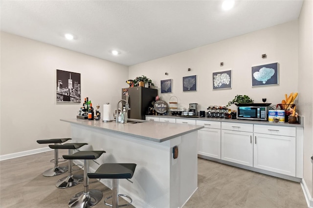 1452 Mickelson Ct, Davenport, FL 33896 - kitchen with stainless steel appliances, a breakfast bar area, white cabinets, a center island with sink, and recessed lighting