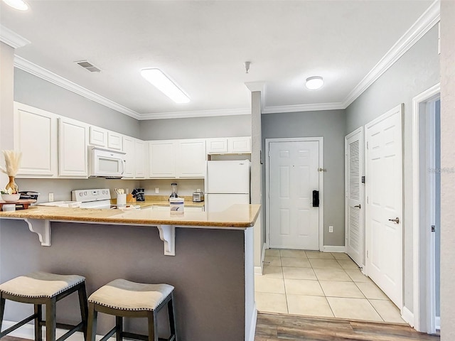 1361 Tuscan Ter Unit 7303, Davenport, FL 33896 - kitchen featuring white appliances, a peninsula, white cabinets, a kitchen breakfast bar, and crown molding