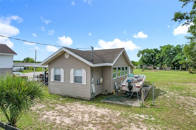 rear view of property featuring a yard, a shingled roof, and a patio area