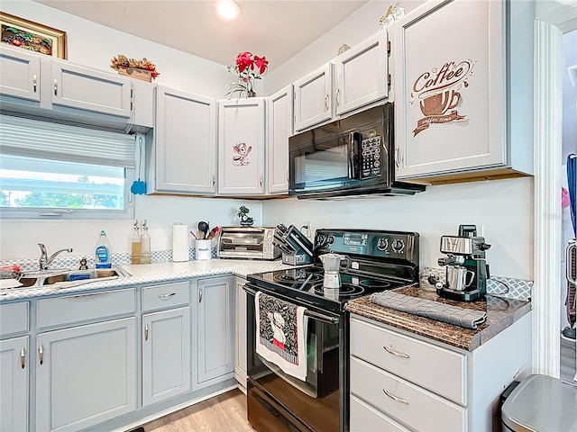 kitchen with black appliances, light wood-style flooring, and light countertops