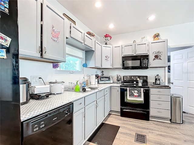 kitchen with black appliances, light wood-type flooring, light countertops, and recessed lighting