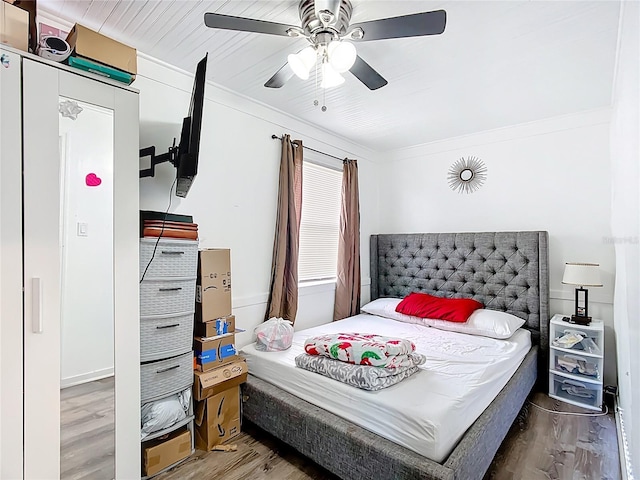 bedroom with wood finished floors, a ceiling fan, and ornamental molding