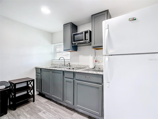 kitchen with black appliances, gray cabinetry, light countertops, and light wood-style floors