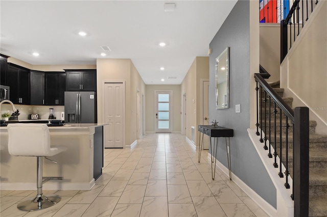 4547 Narrative Ln, Kissimmee, FL 34746 - kitchen featuring stainless steel appliances, dark cabinetry, light marble finish flooring, recessed lighting, and a kitchen breakfast bar