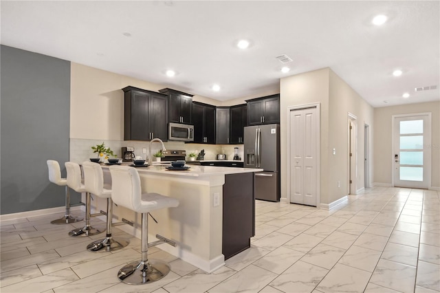 4547 Narrative Ln, Kissimmee, FL 34746 - kitchen featuring appliances with stainless steel finishes, a peninsula, a kitchen bar, light countertops, and decorative backsplash